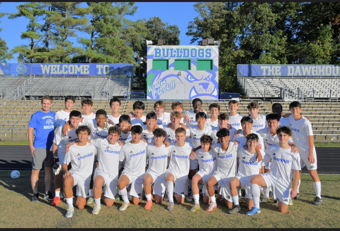 The Boys' Varsity Soccer Team poses for a media day picture. Coach Stephen Hauschild can be seen on the very left.