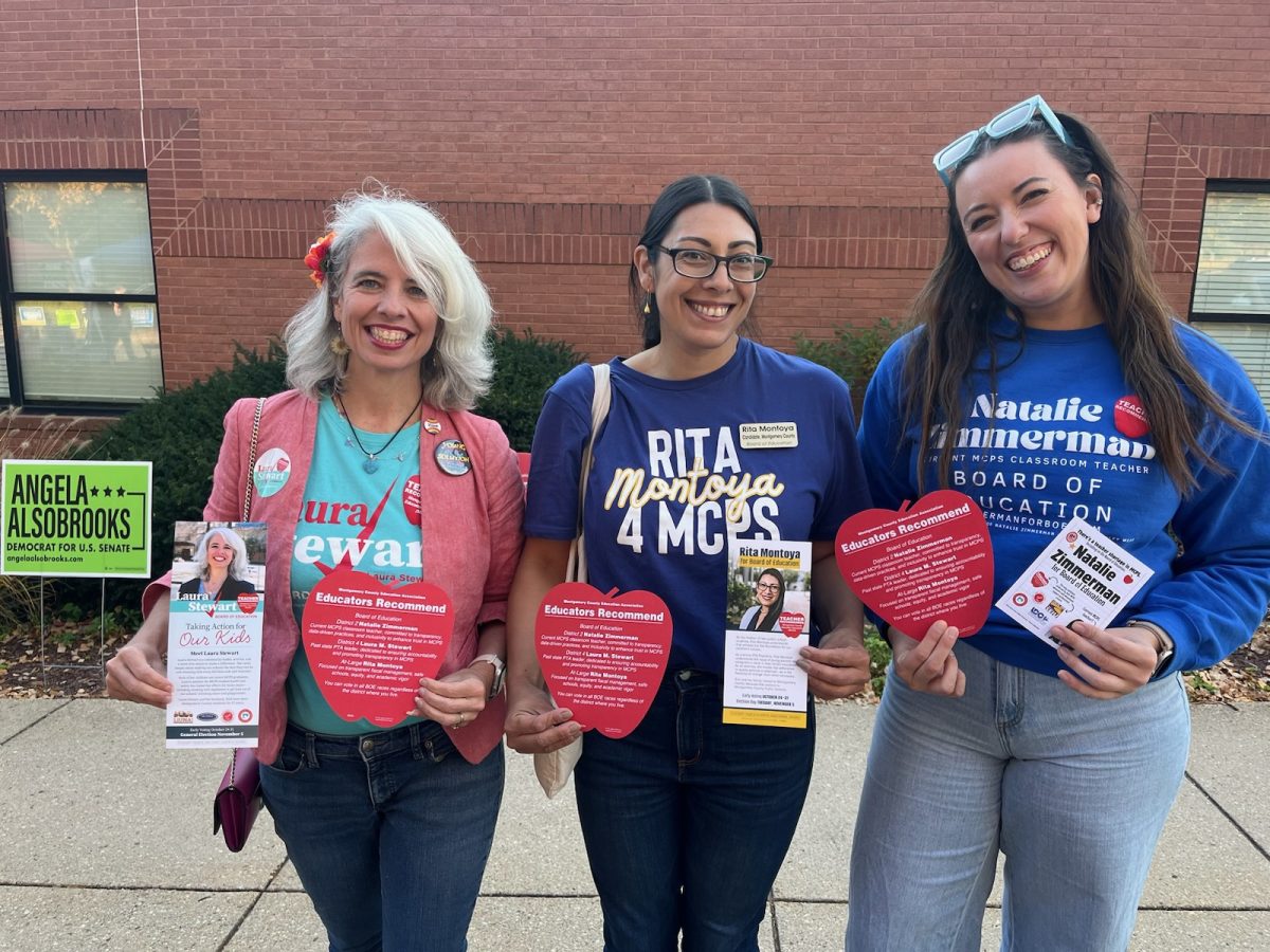 Left to right: Laura Stewart, Rita Montoya, and Natalie Zimmerman pose with campaign literature and MCEA Apple Ballots outside a school.