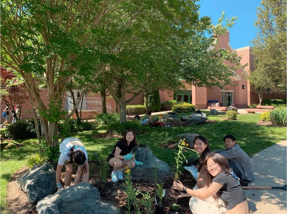 After growing the plants in the WCHS green house, WCHS Gardening Club members are depicted planting them in the surrounding memorial garden area. Aside from beautifying the school, these plants together function as an environmentally friendly rain garden.